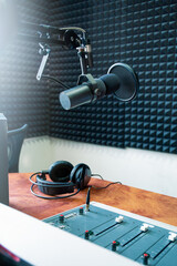 Professional podcast microphone setup in soundproof studio with sound mixer and headphones on desk,...