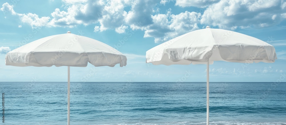 Poster Close up of two closed white canvas beach umbrellas set against a backdrop of the sea and a blue sky with clouds. with copy space image. Place for adding text or design