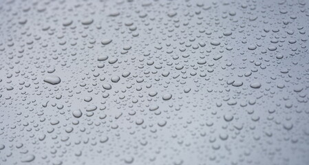 Small droplets of water on a matte gray background, close-up. Rain on a flat surface, condensation on glass