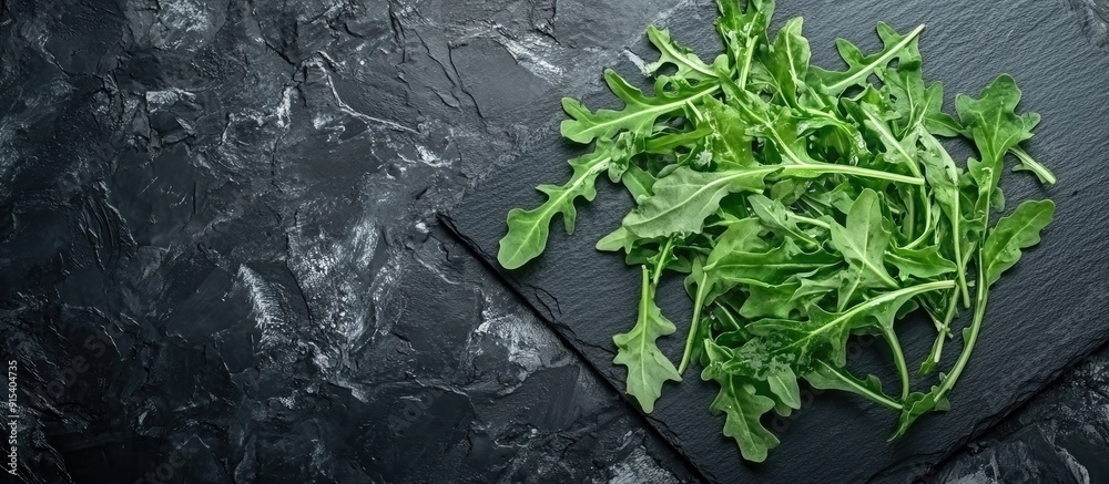 Poster top view of arugula on black slate featuring copy space