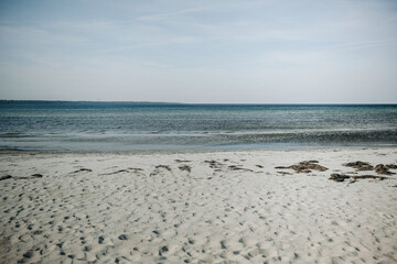 Serene beach view with soft sand and tranquil waters under a clear sky in late afternoon