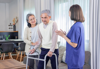Obraz premium old asian man patient trying to walk by using walker,being assist by a nurse caregiver and a senior wife standing and supporting beside him,concept of elderly health care,homecare,home health nursing