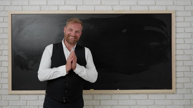Man college teacher in classroom in front of chalkboard explaining lesson for students, writing simple math tasks. Education concept.