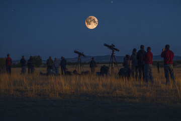 Group of astronomers watching and photographing moon eclipse at night