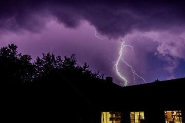 Lightning in urban skies over the house rooftops
