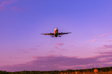 Plane lands at the airport in a colorful sunset, purple sky with pink clouds