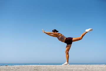 Obraz premium Woman Balancing on One Leg by the Ocean