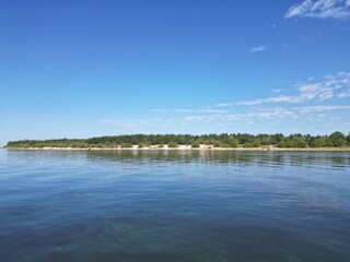 Island on a lake with white sand on a sunny day.