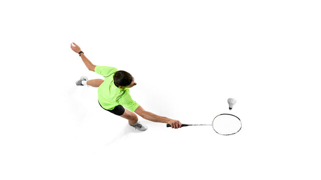 Top view of badminton player, man in green t-shirt and black shorts in motion, training, playing isolated on white background. Concept of sport, competition, active and healthy lifestyle - Powered by Adobe