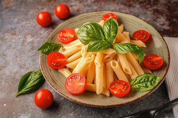 Delicious pasta with aromatic basil and tomatoes close-up on a dish.