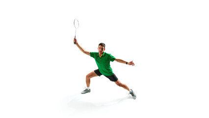 Young guy in green polo shirt, badminton player with racket attending in focus, playing with concentration isolated on white background. Concept of sport, competition, active and healthy lifestyle