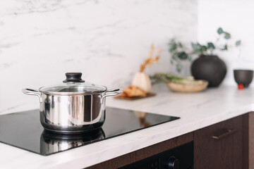 Glass ceramic stove with metal pot in modern kitchen