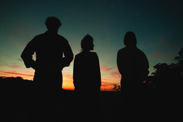 Meeting of people in darkness, some men and one woman, looking into the distance under dark sky of night	