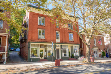 Traditional American brick buildings with shops on ground floor along a tree lined street in a historic downtown on a sunny autumn day