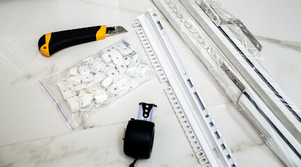 Automatic cornices for curtains in white. Stationery knife, roulette and hooks for curtains