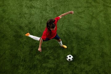 Aerial view of female soccer player preparing to hit ball in motion on green lash stadium during final game. Score goal. Concept of women and sport, team games, movement, victory, action. Ad