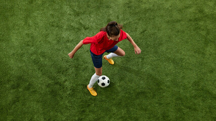 Aerial view of female football athlete training dribbling technique on green lush stadium. Workout for win. Concept of women and sport, team games, movement, victory, action. Ad