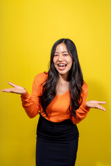 A woman in an orange shirt and black skirt is smiling and making a silly face