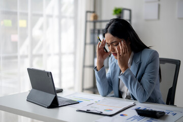 A woman in a blue suit is on the phone, looking very stressed