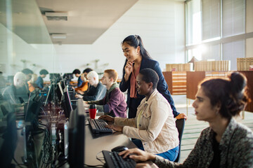 Teacher assisting students in a computer lab classroom