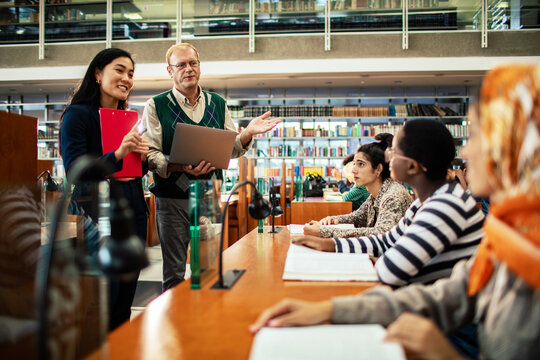 University professor giving lecture to diverse students in library