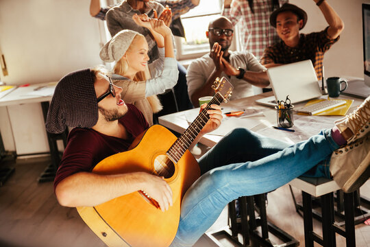 Casual office jam session with guitar and team enjoying music