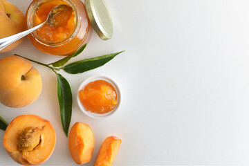 Jars with peach jam and fruit on white table top