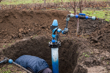 A worker installs a water intake unit in a well. Installation of the well walls of a pumping station