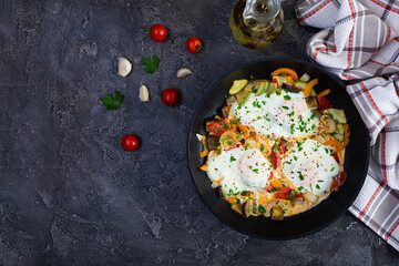 Shakshuka in a frying pan.  Fried eggs with tomato, pepper, zucchini and herbs
