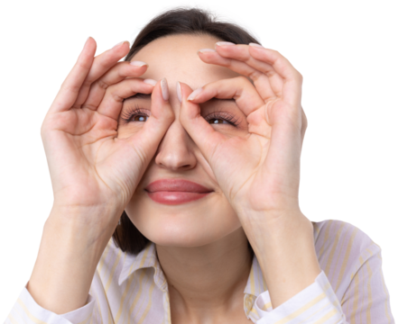 Close up portrait of attractive quirky young woman making binoculars with hands showing ok gesture on white studio background.