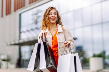 Pretty young woman walking down with shopping bags on city street.  Sale, purchases, shopping, lifestyle concept.