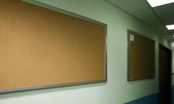 Empty Bulletin Board in Office Corridor: A simple and clean photograph of a blank corkboard in a hallway, ready for your message.  Perfect for presentations, announcements, or simply adding a touch of