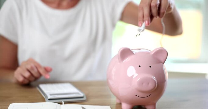 Female hand inserting electronic plug into piggy bank closeup 4k movie slow motion. Energy saving concept