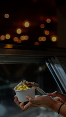 Close up hand of a person holding a cup of ice cream with blurred background