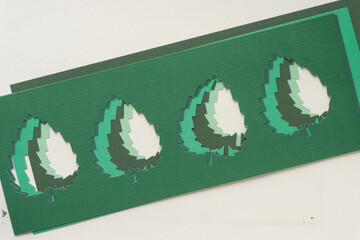 slightly staggered pile of layered machine-cut stencils with paper leaf shapes
