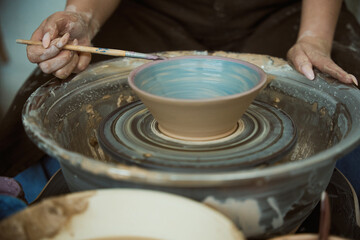 Close up detail view at an artist making clay pottery on a spin wheel
