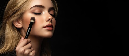 Obraz premium A woman s hand is using a brush to apply makeup on a beautiful blonde female model Copy space