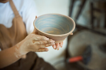 Close up of woman holding a finished clay product in workshop