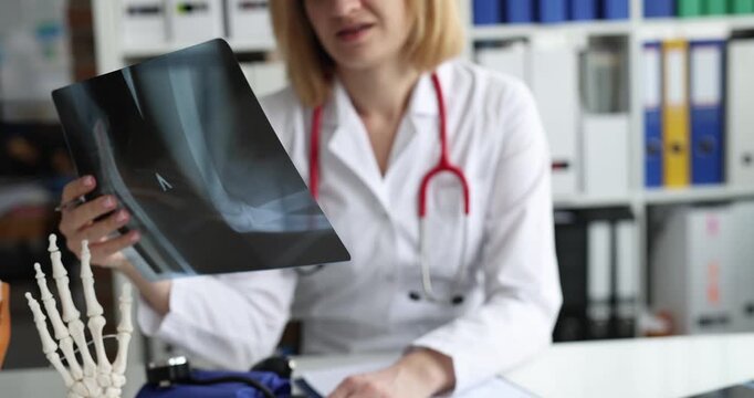 Doctor examines x-ray of patient with broken arm. Traumatologist and fracture treatment concept
