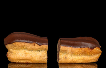 Two halves of an eclair with cream, macro, isolated on a black background.