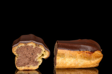 Two halves of an eclair with cream, macro, isolated on a black background.