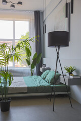 stylish discreet interior of the sleeping area in a modern studio in white-gray colors with green plants. daylight and no people inside