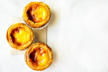 Pastel de nata or Pastel de Belém. Bright, golden, crispy traditional Portuguese dessert on a white background. Copy space for the text. Banner. Advertising 