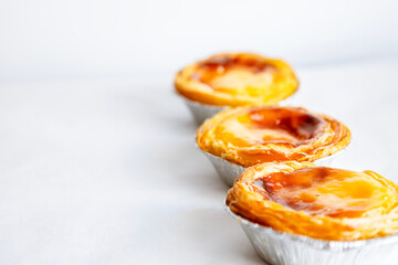 Pastel de nata or Pastel de Belém. Bright, golden, crispy traditional Portuguese dessert on a white background. Copy space for the text. Banner. Advertising 