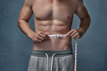 Body, fitness and tape measure with shirtless man in studio for masculine health, strength or...