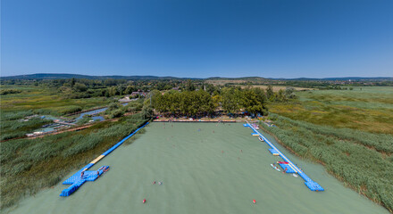 Beach in Lake Balaton. People bathing in the water of lake in  hot summertime. There are many...