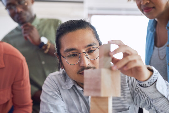 Office, employees and man with building blocks for problem solving, solution and educational. Diversity, people and concentrate with game for fun, project and creativity as graphic designer.