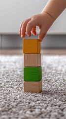 A child's hand stacking colorful wooden blocks in kindergarten