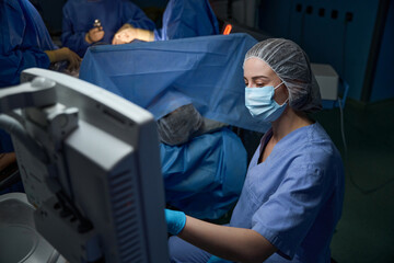 Female surgeon using monitor in operating room