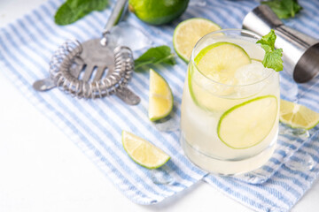 Summer cold refreshment limeade cocktail, cold alcohol or non-alcohol beverage with limes, mint and ice cubes, copy space